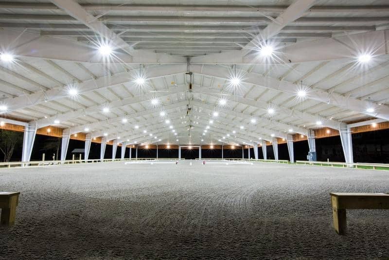 Indoor horse arena with lights on at night.