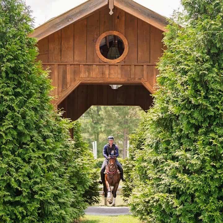 Cross Country rider coming through arch with brush on either side